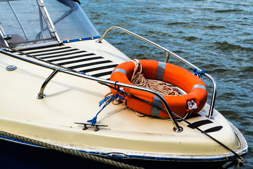 sideview of boat in the water with insurance and orange life buoy