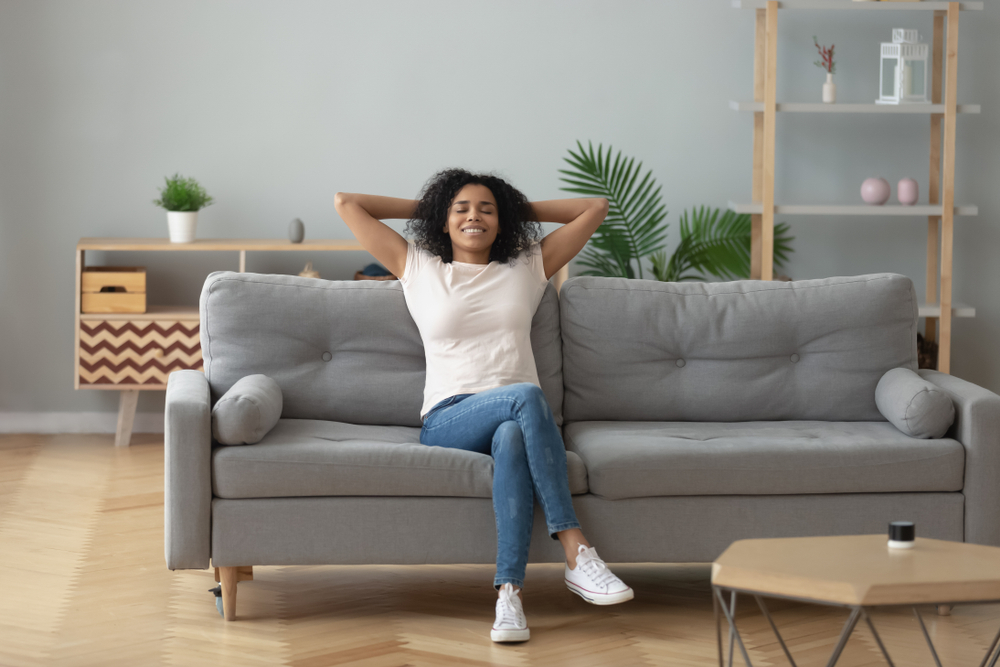Happy african American young woman in her first-time rental apartments couch
