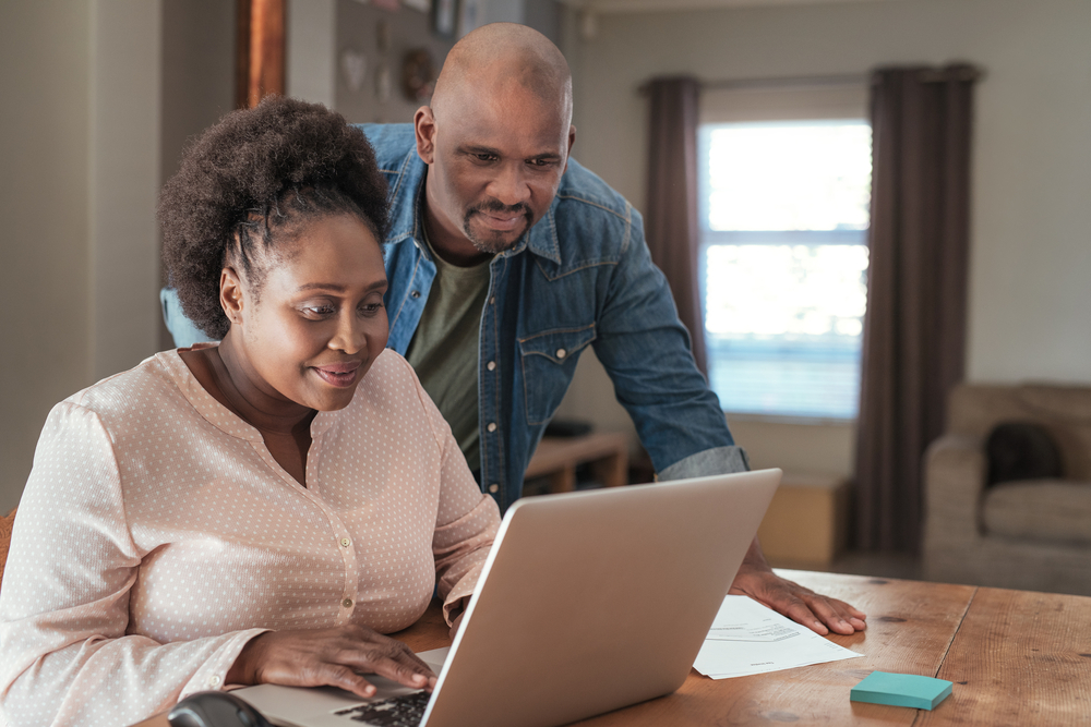 happy african american couple looking for motorcycle insurance in a laptop