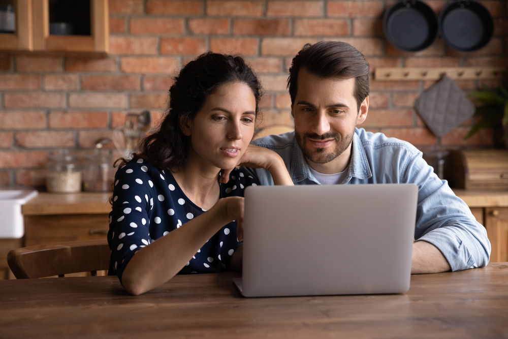 young couple researching life insurance on laptop