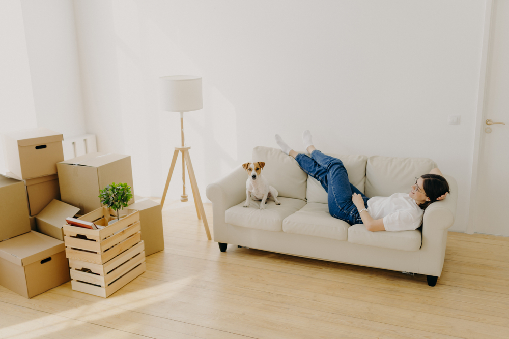woman sitting in new apartment with dog on the couch