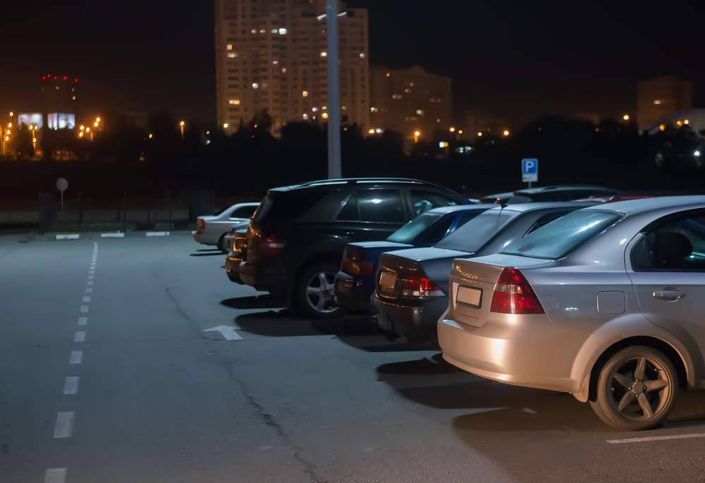 cars parked at night in parking lot under light