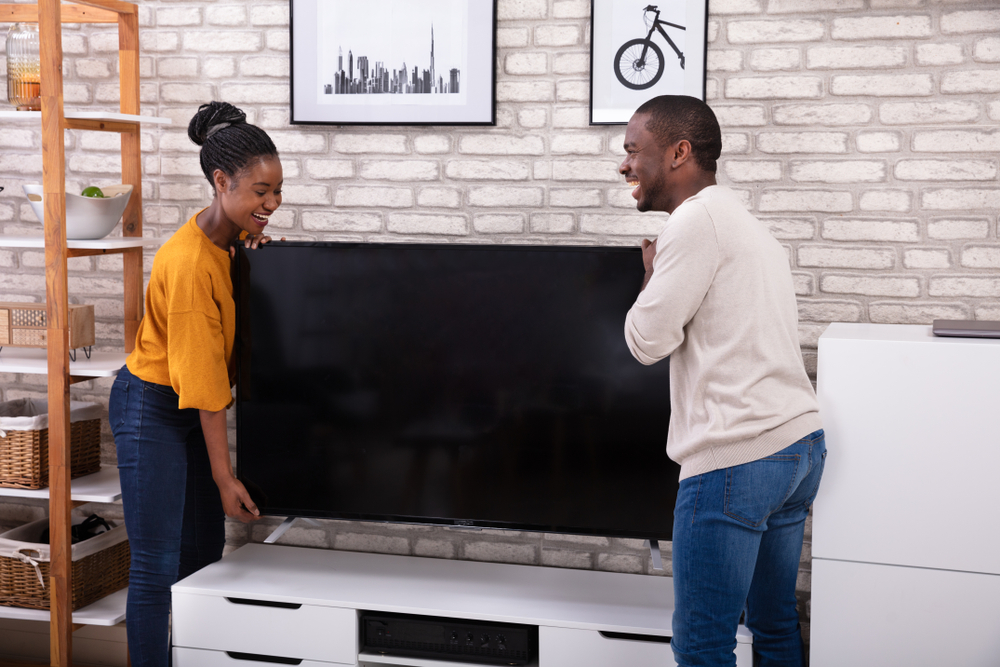 young african american couple moving tv into new apartment