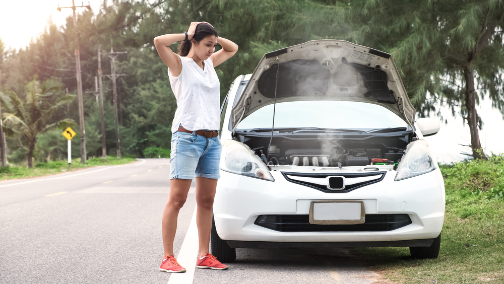 woman standing next to car overheating with hood up