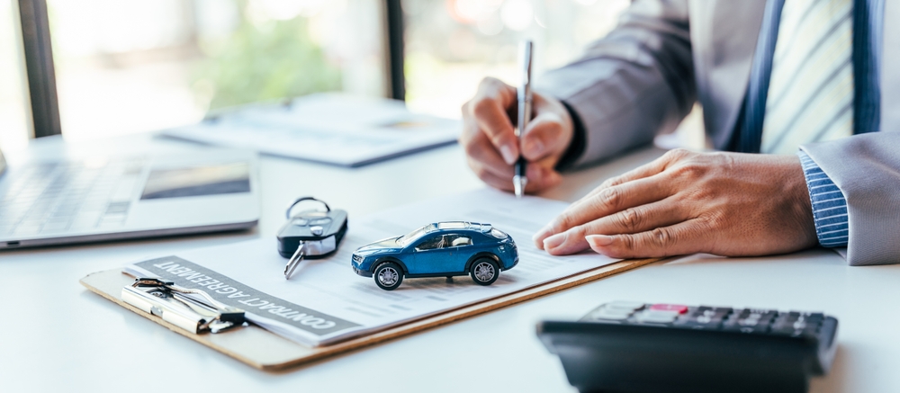 person calculating insurance premium with calculator and documents at desk
