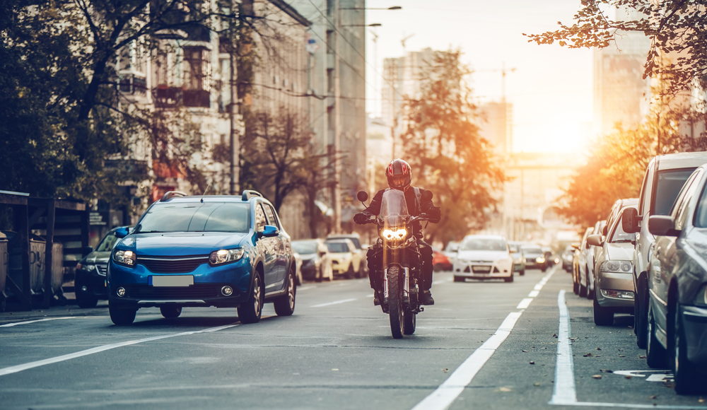 car and motorcycle driving side-by-side on road