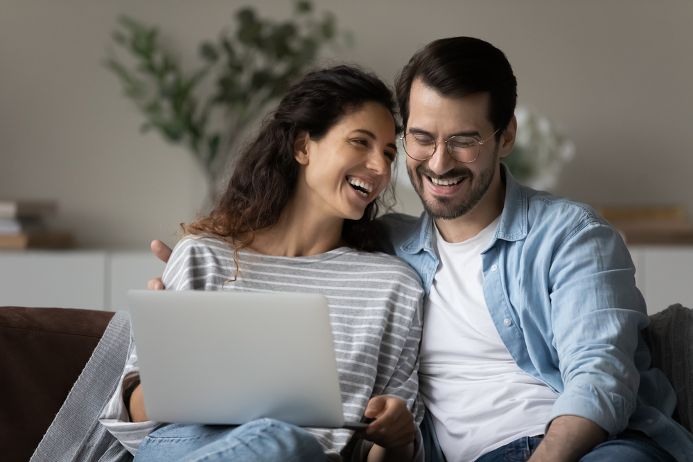 couple smiling look at laptop