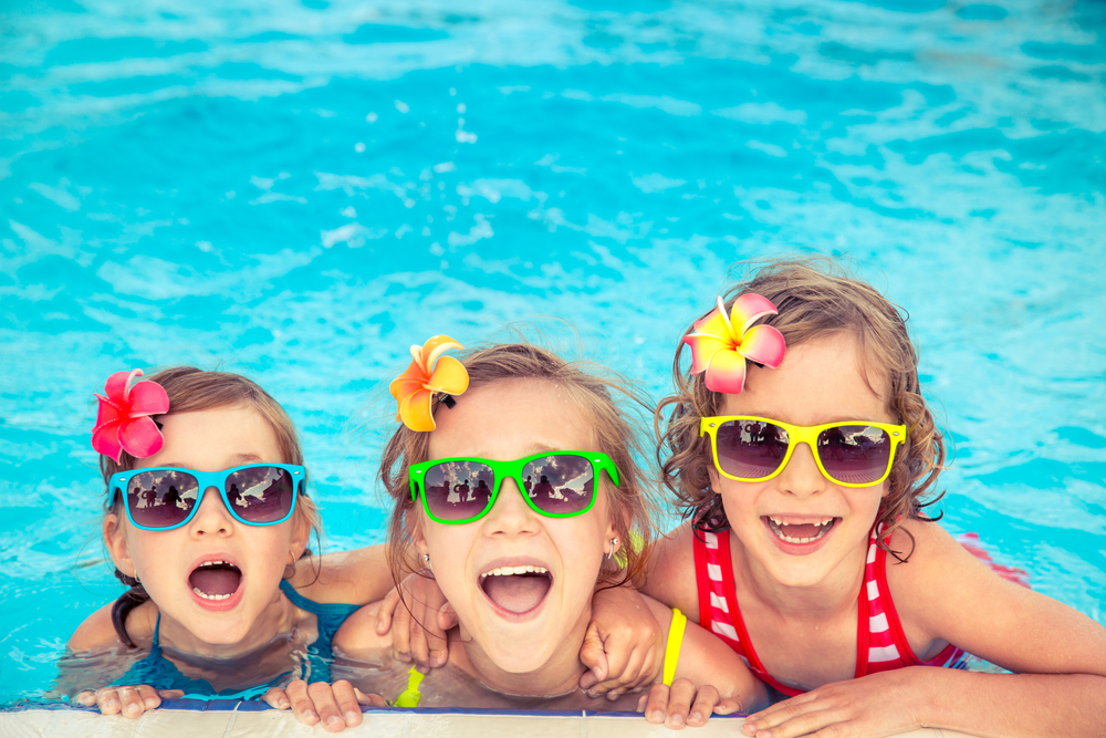 Three little girls in fun sunglasses in the pool